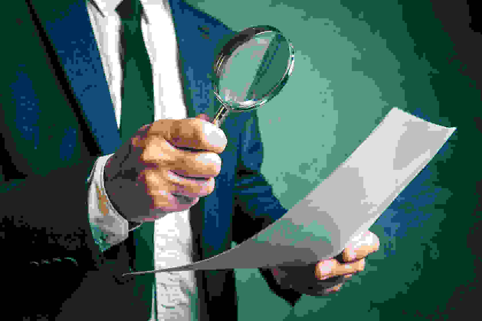 58518891 - Tax Inspector Investigating Financial Documents Through Magnifying Glass, Forensic Accounting Or Financial Forensics, Inspecting Offshore Company Financial Papers, Documents And Reports.