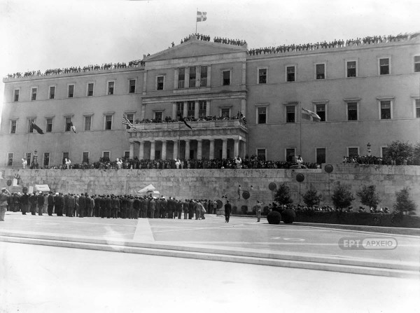 18 Οκτωβρίου 1944. Πλήθος κόσμου έχει κατακλύσει το κτήριο της Βουλής των Ελλήνων για να παρακολουθήσει την κατάθεση στεφάνου στο Μνημείο του Αγνώστου Στρατιώτη από τον πρωθυπουργό της Απελευθέρωσης Γεώργιο Παπανδρέου, Αρχείο ΕΡΤ – Πέτρος Πουλίδης