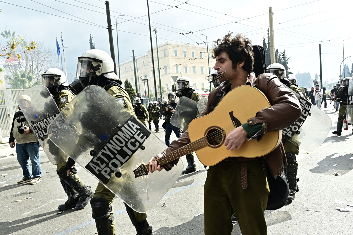 Τέμπη: Μουσικός παίζει κιθάρα εν μέσω των σοβαρών επεισοδίων με βόμβες μολότοφ και χημικά στο Σύνταγμα